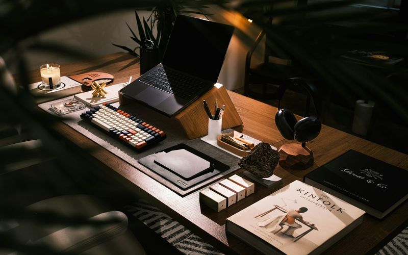 Escritorio con laptop abierta, libros apilados y accesorios de trabajo